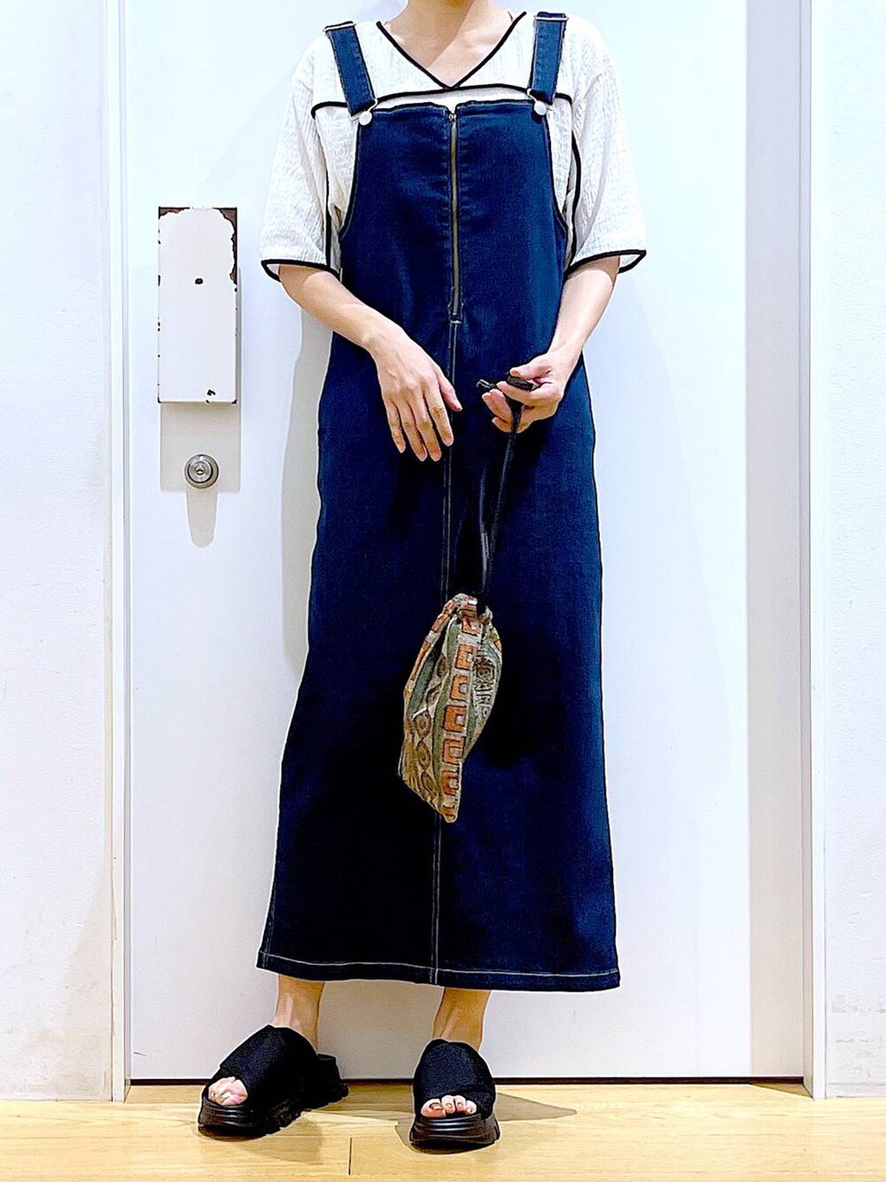 ブルー系のジャンパースカート、ブラウン系のショルダーバッグ、ブラック系のサンダルを着用したレディースの夏コーディネートの6枚目の写真