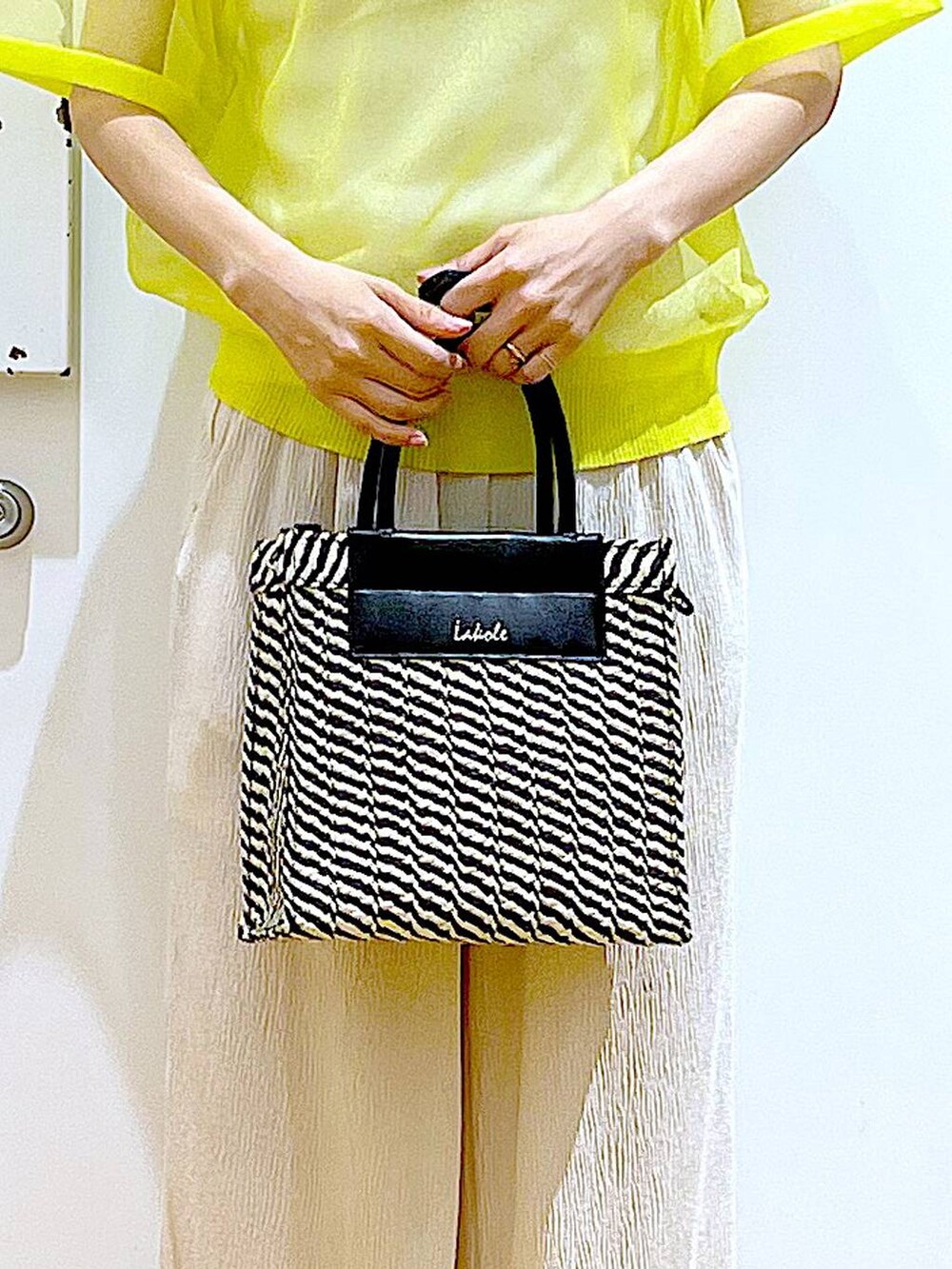 イエロー系のニット/セーター、ホワイト系のその他パンツ、ホワイト系のニット/セーターを着用したレディースの夏コーディネートの9枚目の写真