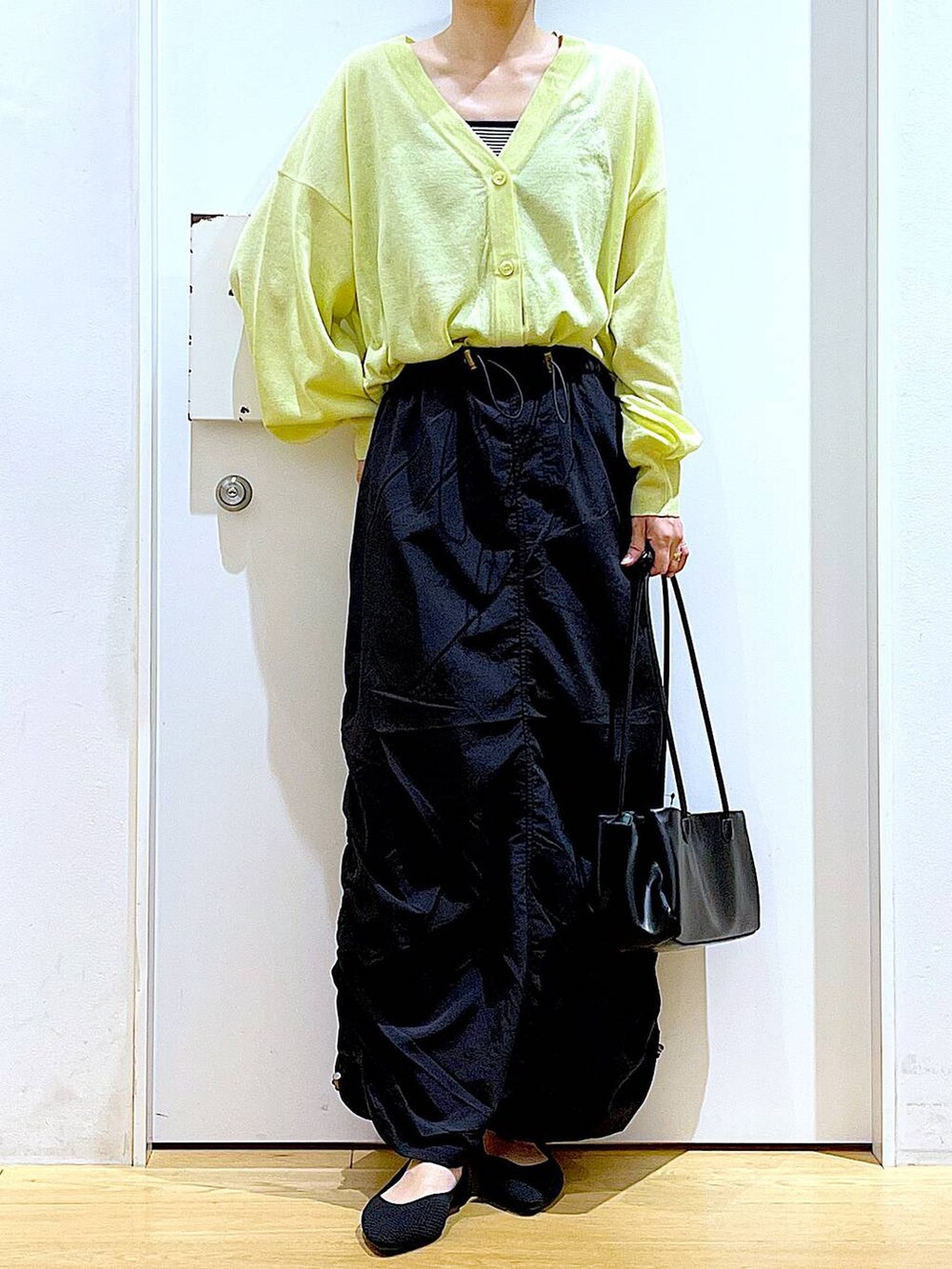 ホワイト系のキャミソール、グリーン系のカーディガン/ボレロ、ブラック系のトートバッグを着用したレディースの春コーディネートの6枚目の写真