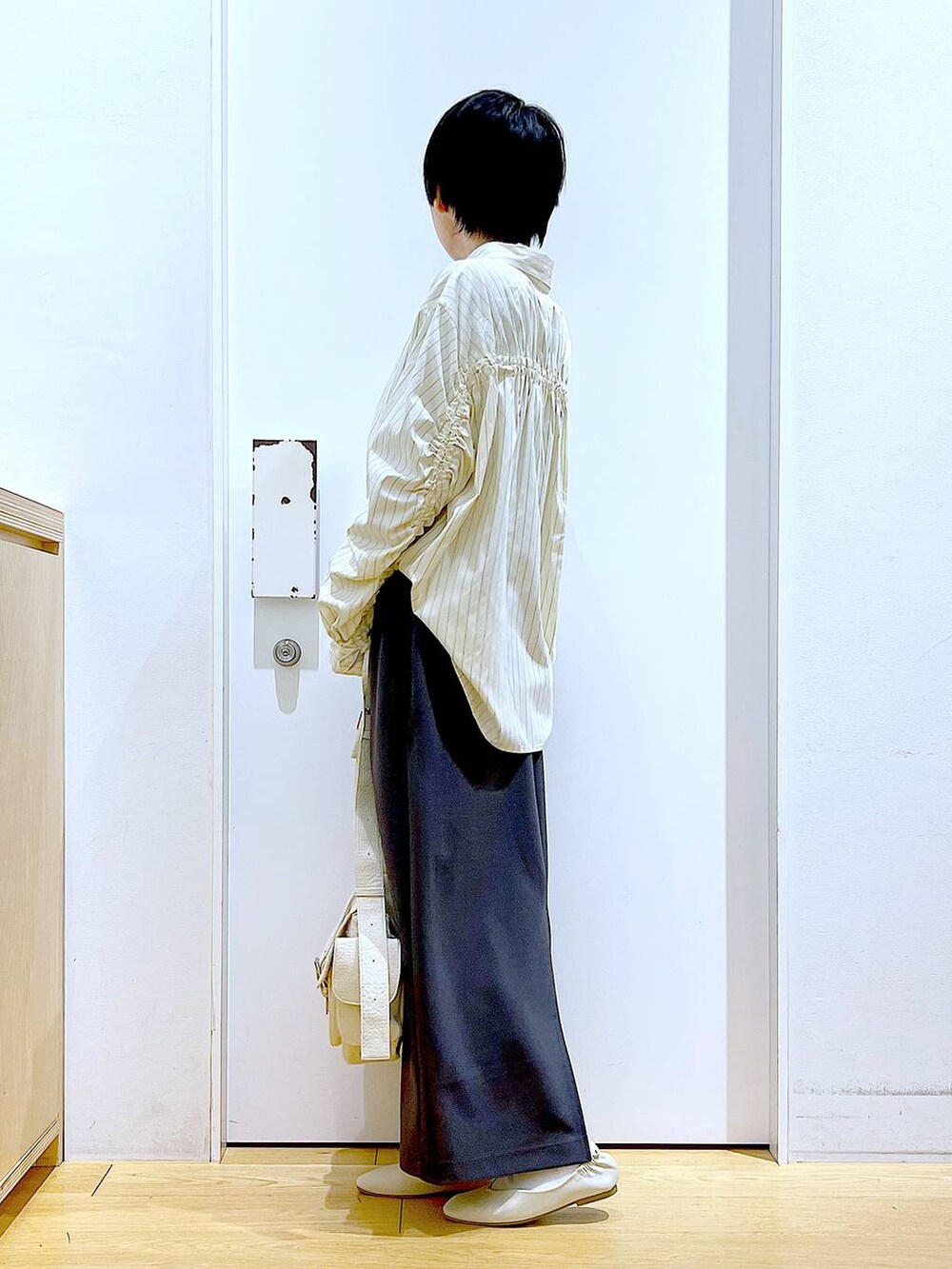 ホワイト系のパンプス、ベージュ系のシャツ/ブラウス、グレー系のスカートを着用したレディースの春コーディネートの3枚目の写真