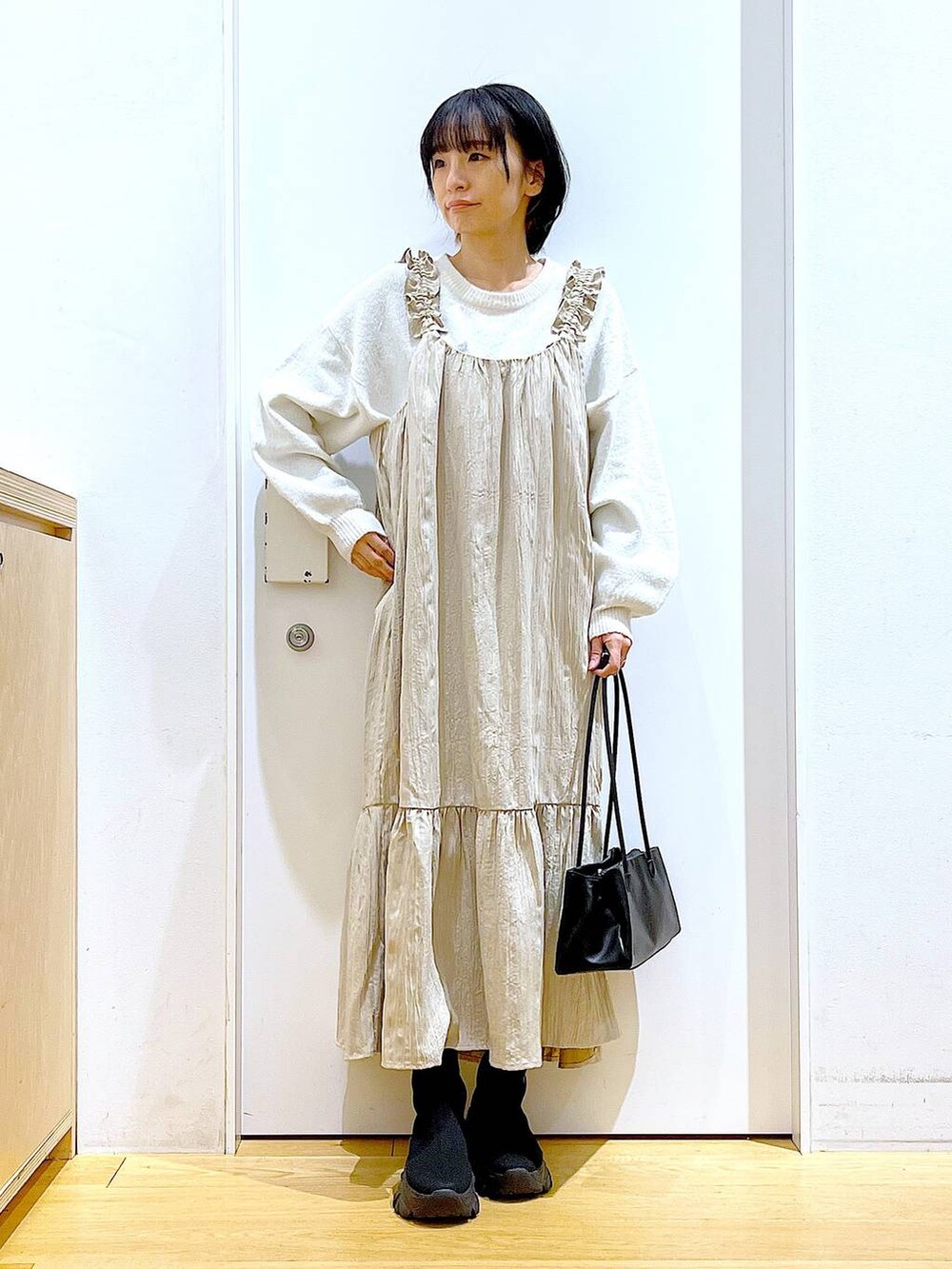 ブラック系のブーツ、ブラック系のトートバッグ、ベージュ系のニット/セーターを着用したレディースの冬コーディネートの2枚目の写真