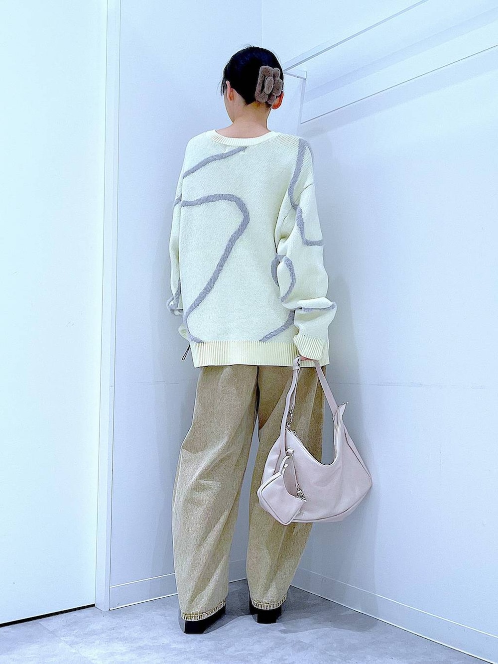 ベージュ系のデニムパンツ、ブラック系のブーツ、ホワイト系のショルダーバッグを着用したレディースの冬コーディネートの6枚目の写真