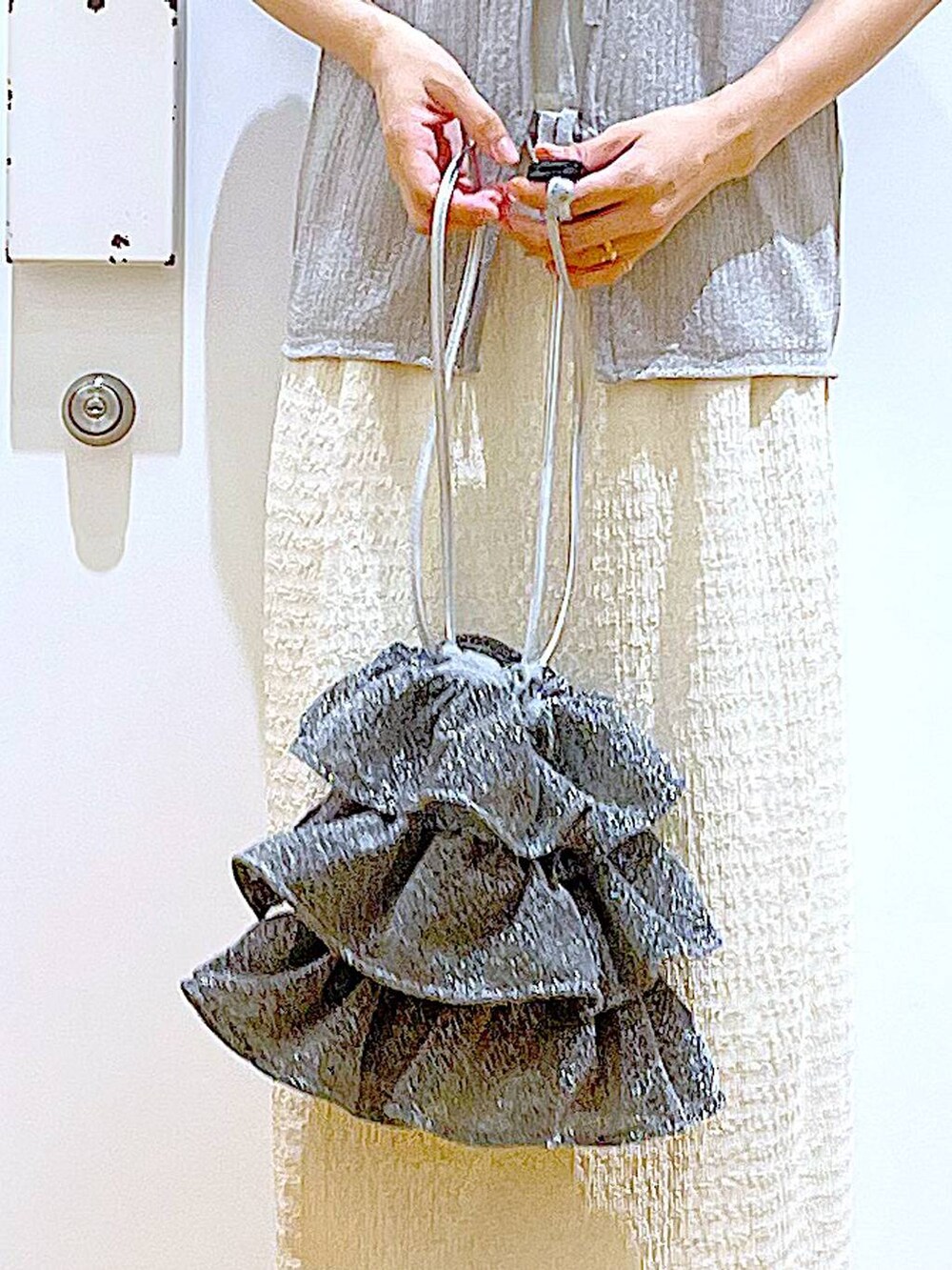 シルバー系のショルダーバッグ、ホワイト系のニット/セーター、ホワイト系のサンダルを着用したレディースの夏コーディネートの9枚目の写真