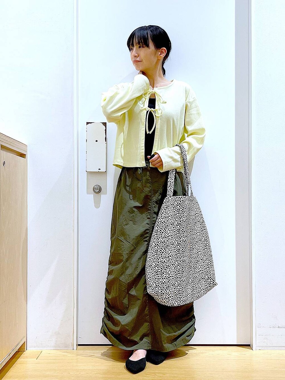 イエロー系のカーディガン/ボレロ、グリーン系のスカート、ベージュ系のトートバッグを着用したレディースの春コーディネートの2枚目の写真