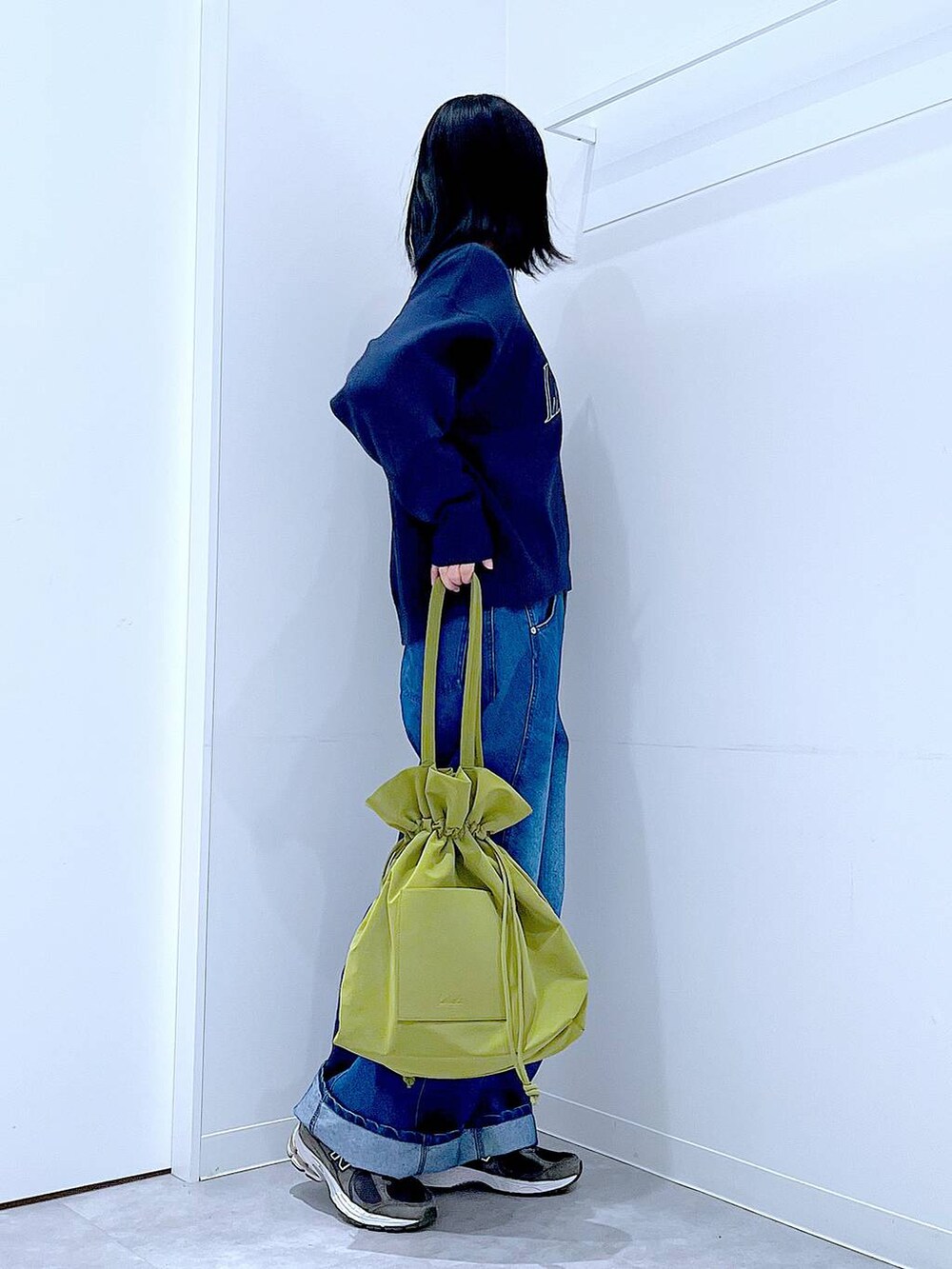 グリーン系のトートバッグ、ブルー系のニット/セーター、ブルー系のデニムパンツを着用したレディースの冬コーディネートの4枚目の写真