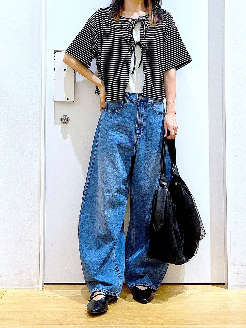 ブラック系のトートバッグ、ブルー系のデニムパンツ、その他のカーディガン/ボレロを着用したレディースの秋コーディネートの6枚目の写真