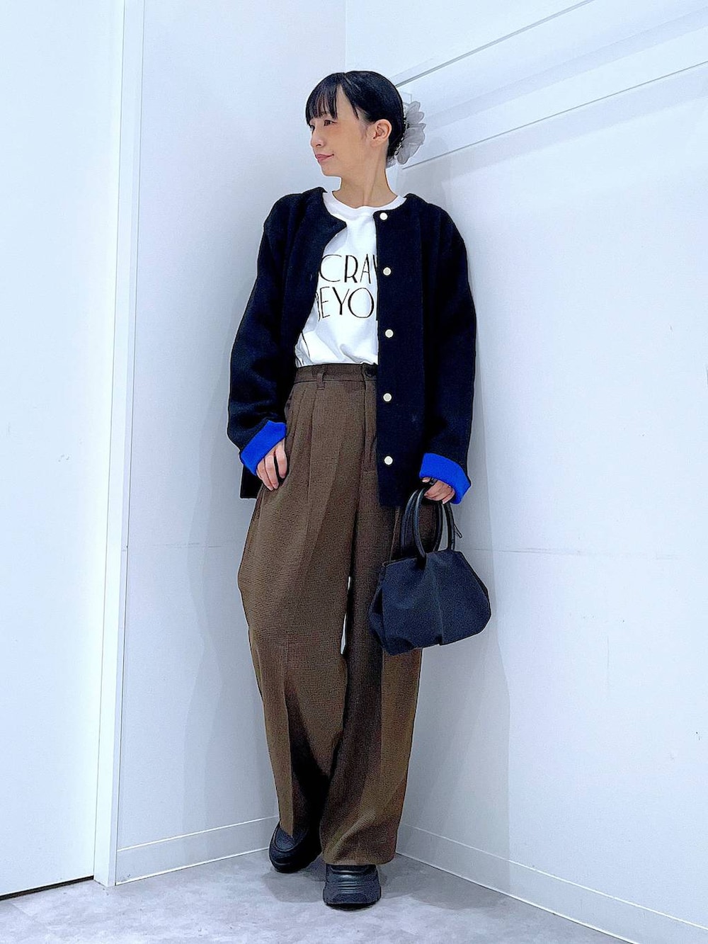 ブラック系のハンドバッグ、ブラウン系のスラックス、ホワイト系のTシャツ/カットソーを着用したレディースの秋コーディネートの2枚目の写真