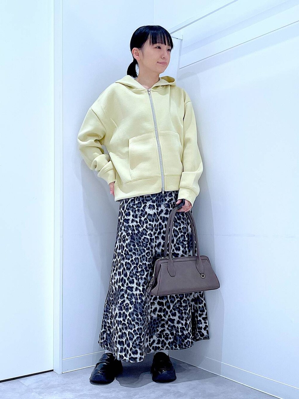 ブラック系のローファー、グレー系のスカート、イエロー系のパーカーを着用したレディースの秋コーディネートの2枚目の写真