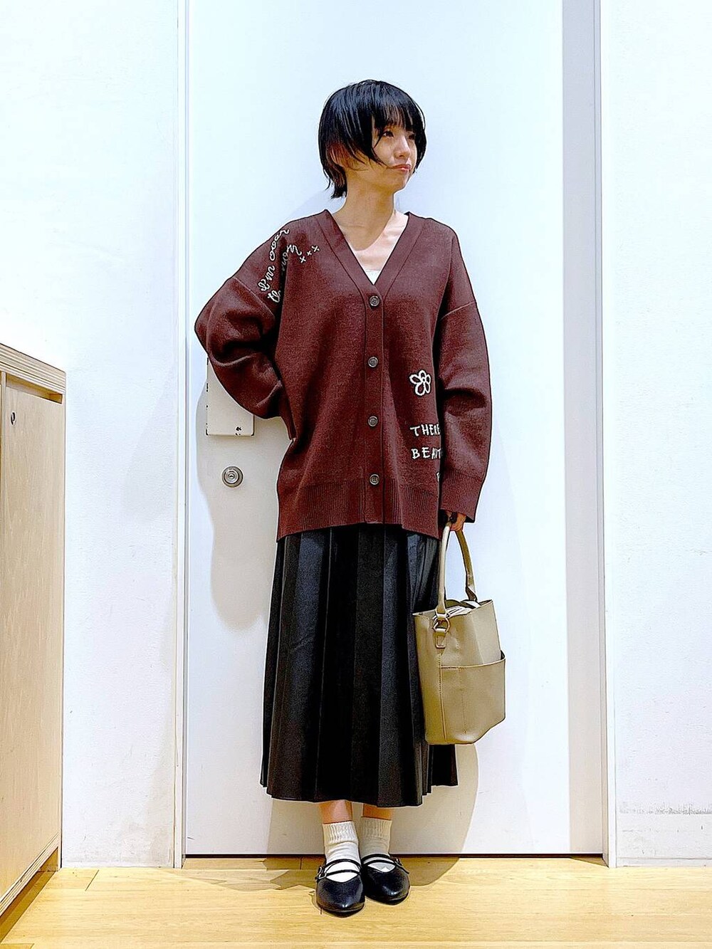 ブラック系のパンプス、ブラック系のスカート、ベージュ系のショルダーバッグを着用したレディースの秋コーディネートの2枚目の写真