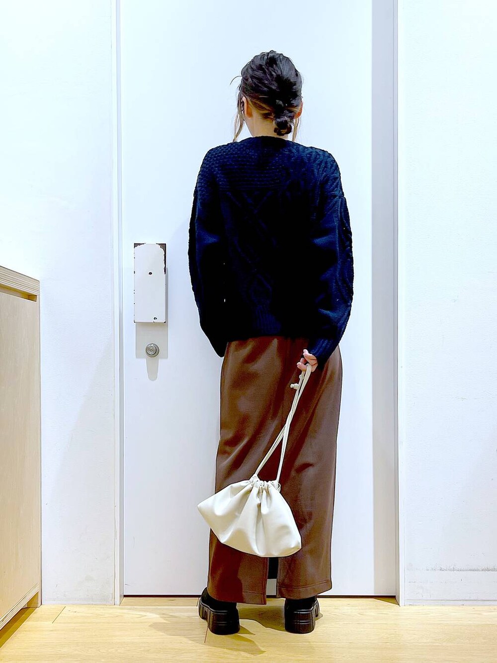 ブラック系のブーツ、ベージュ系のショルダーバッグ、ブラウン系のスカートを着用したレディースの冬コーディネートの5枚目の写真