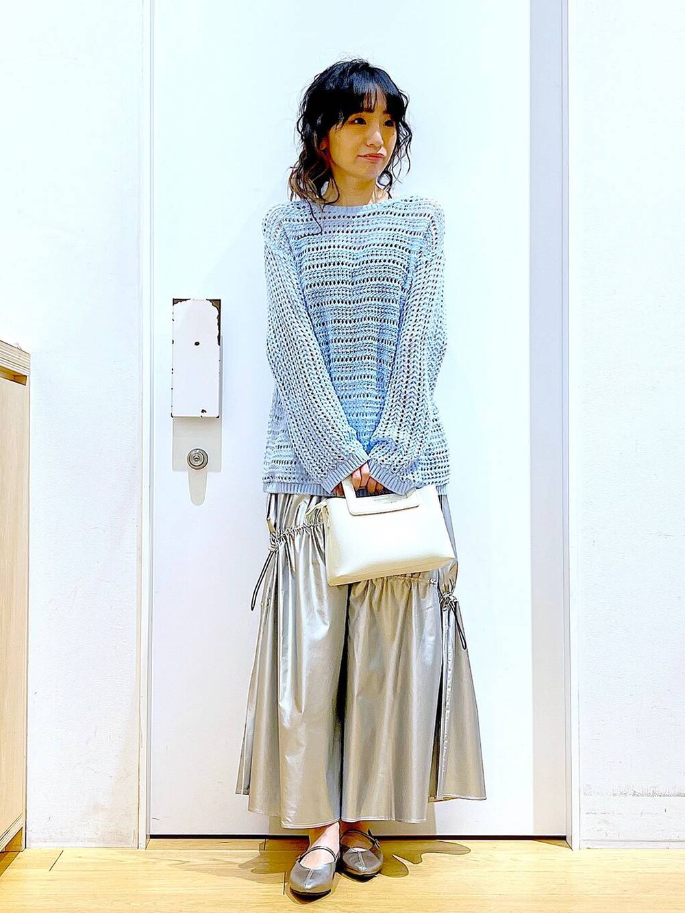 ブルー系のニット/セーター、シルバー系のスカート、ホワイト系のショルダーバッグを着用したレディースの春コーディネートの2枚目の写真