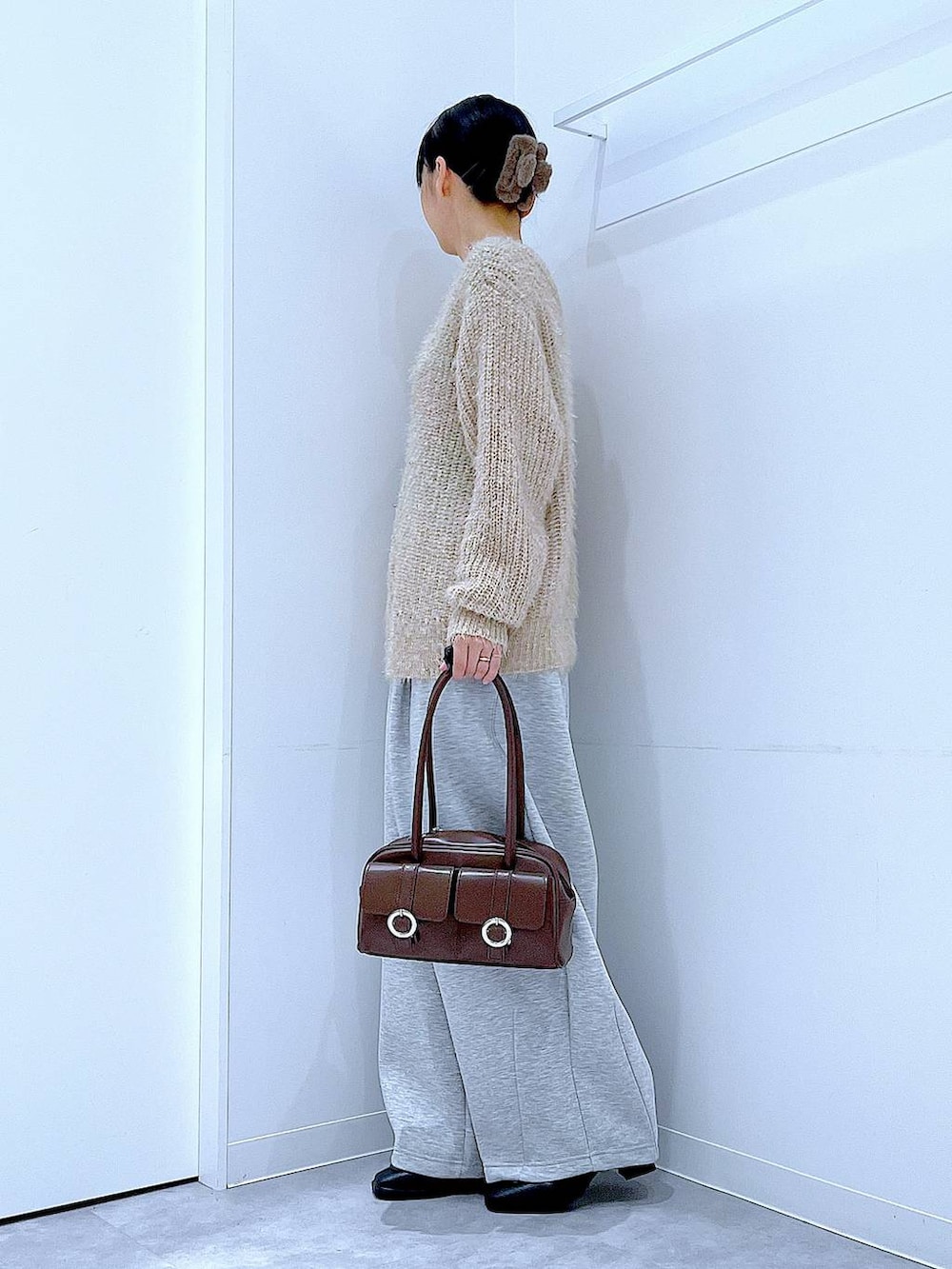 ブラウン系のショルダーバッグ、ブラック系のブーツ、グレー系のスウェットパンツを着用したレディースの冬コーディネートの3枚目の写真