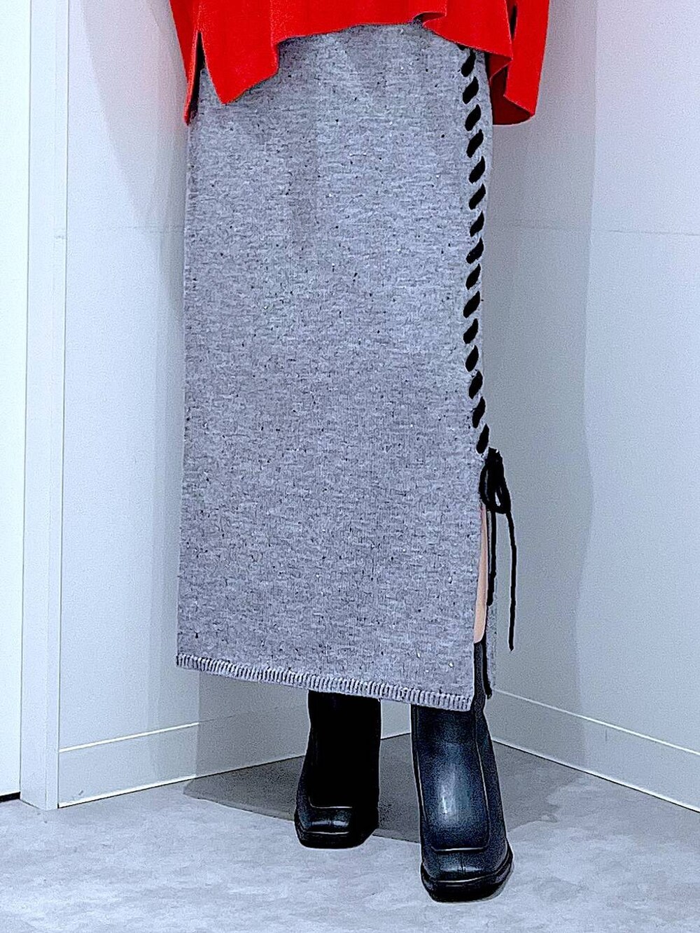 レッド系のニット/セーター、グレー系のスカート、ブラック系のブーツを着用したレディースの秋コーディネートの8枚目の写真