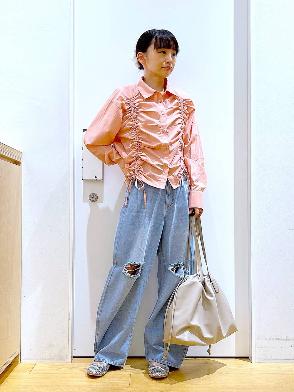 ベージュ系のトートバッグ、ブルー系のデニムパンツ、シルバー系のパンプスを着用したレディースの秋コーディネートの2枚目の写真