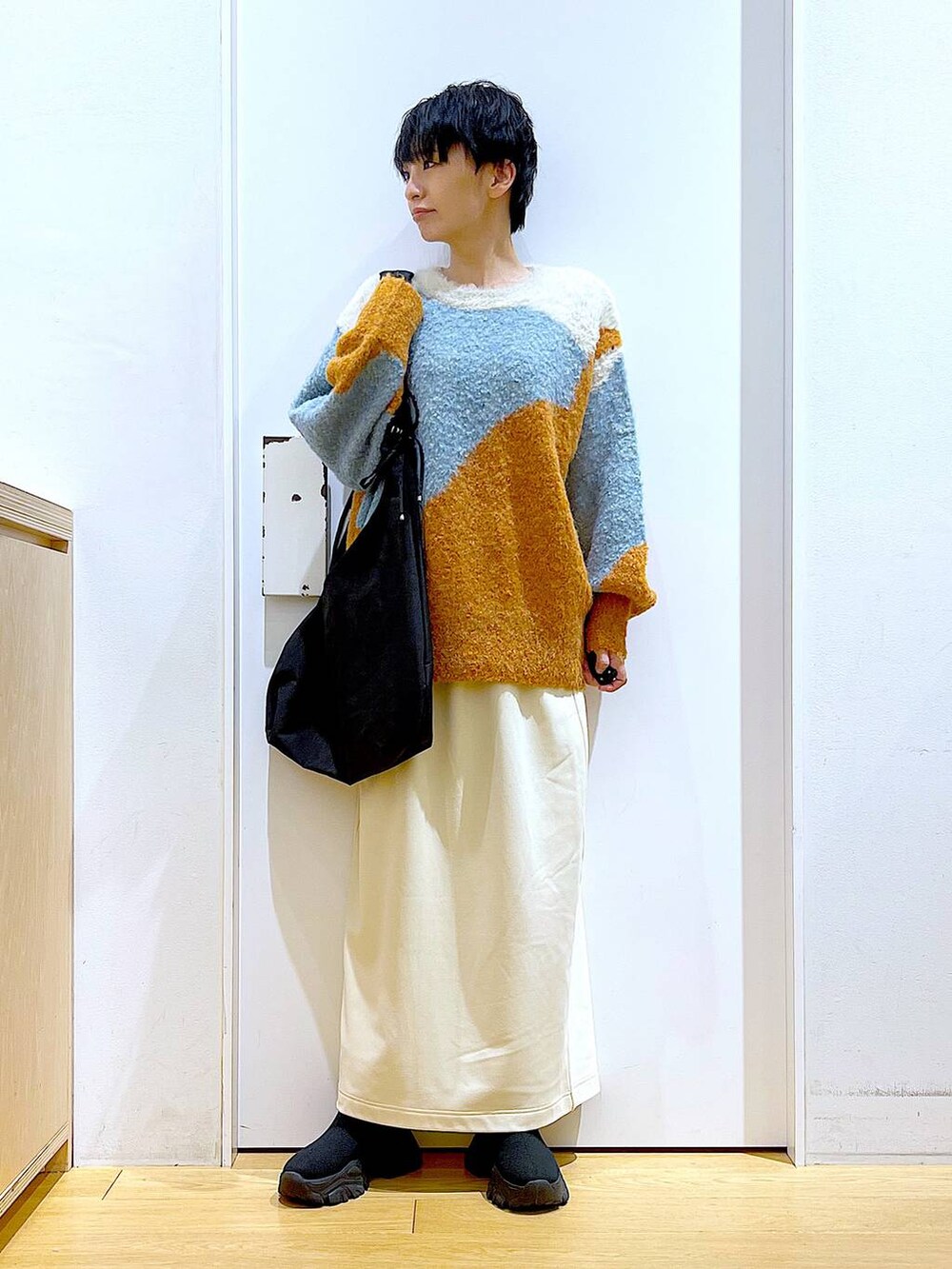 ブラック系のショルダーバッグ、ブラック系のブーツ、オレンジ系のニット/セーターを着用したレディースの冬コーディネートの2枚目の写真