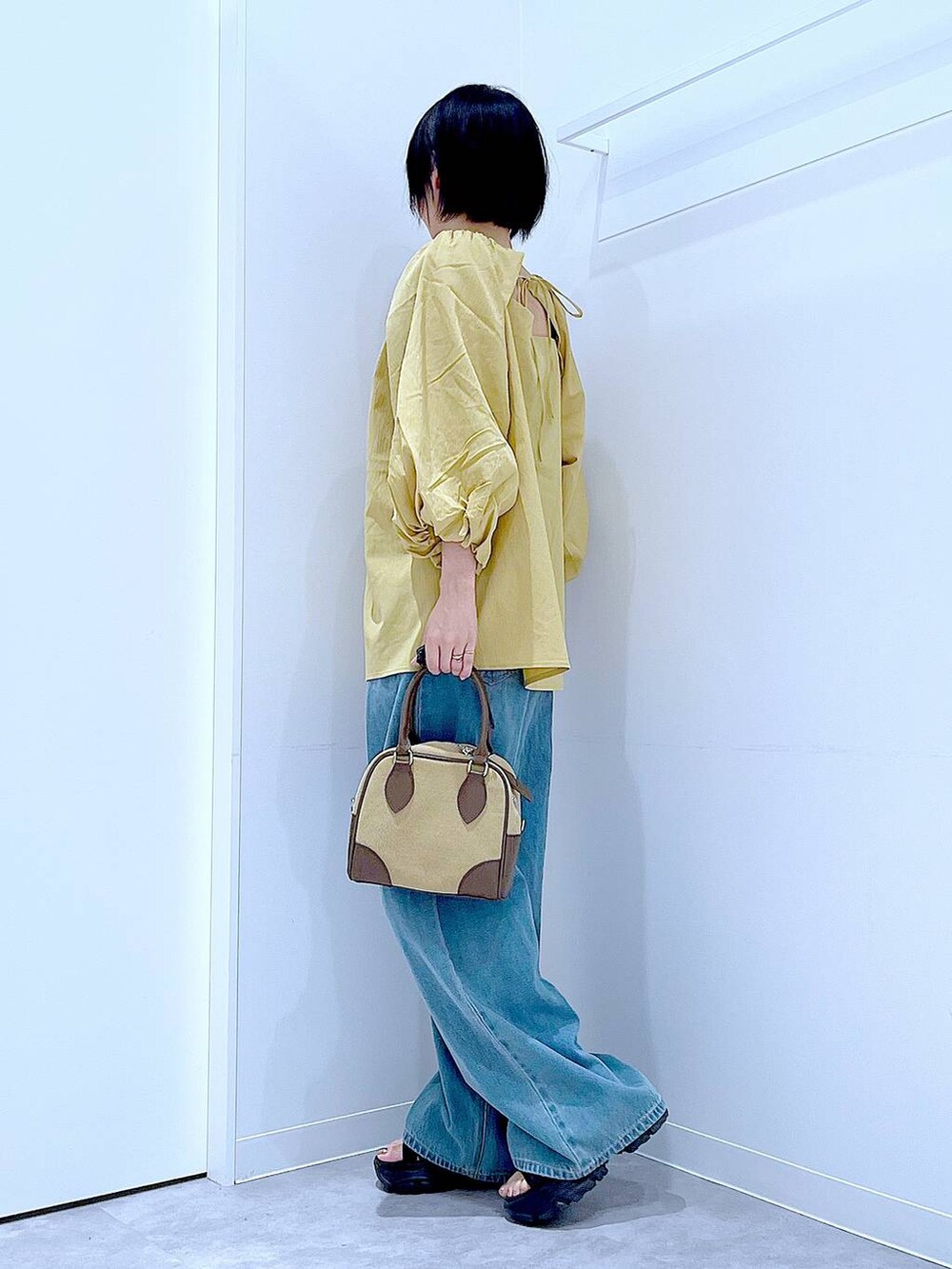 ブラック系のスニーカー、ブルー系のデニムパンツ、イエロー系のシャツ/ブラウスを着用したレディースの秋コーディネートの3枚目の写真