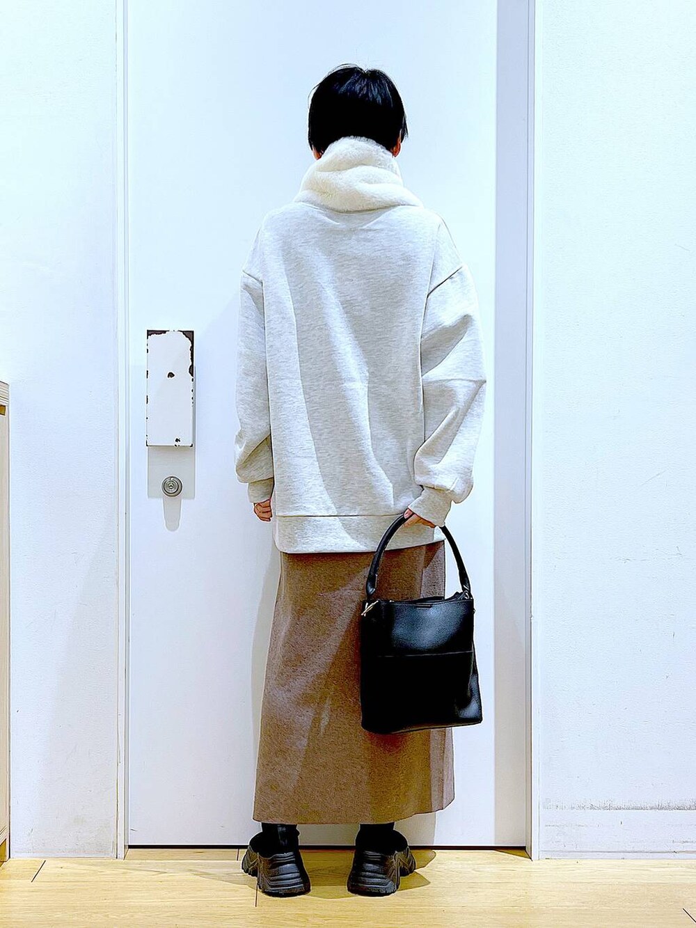 ブラック系のショルダーバッグ、ブラック系のブーツ、ブラウン系のスカートを着用したレディースの冬コーディネートの5枚目の写真