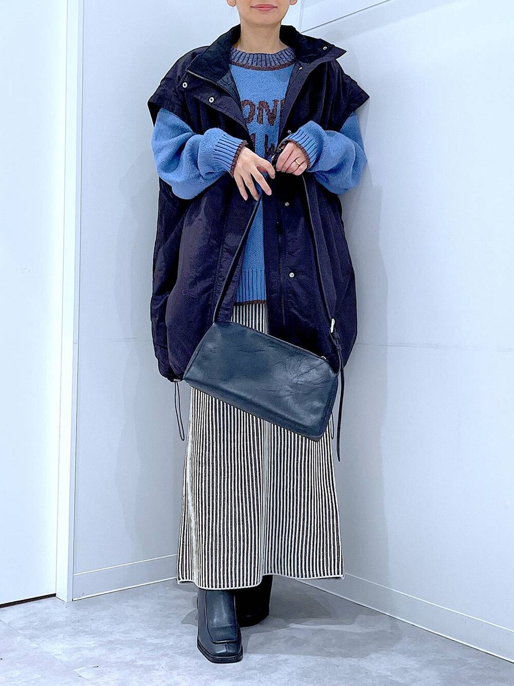 ブラック系のブルゾン、ベージュ系のスカート、ブラック系のブーツを着用したレディースの冬コーディネートの6枚目の写真