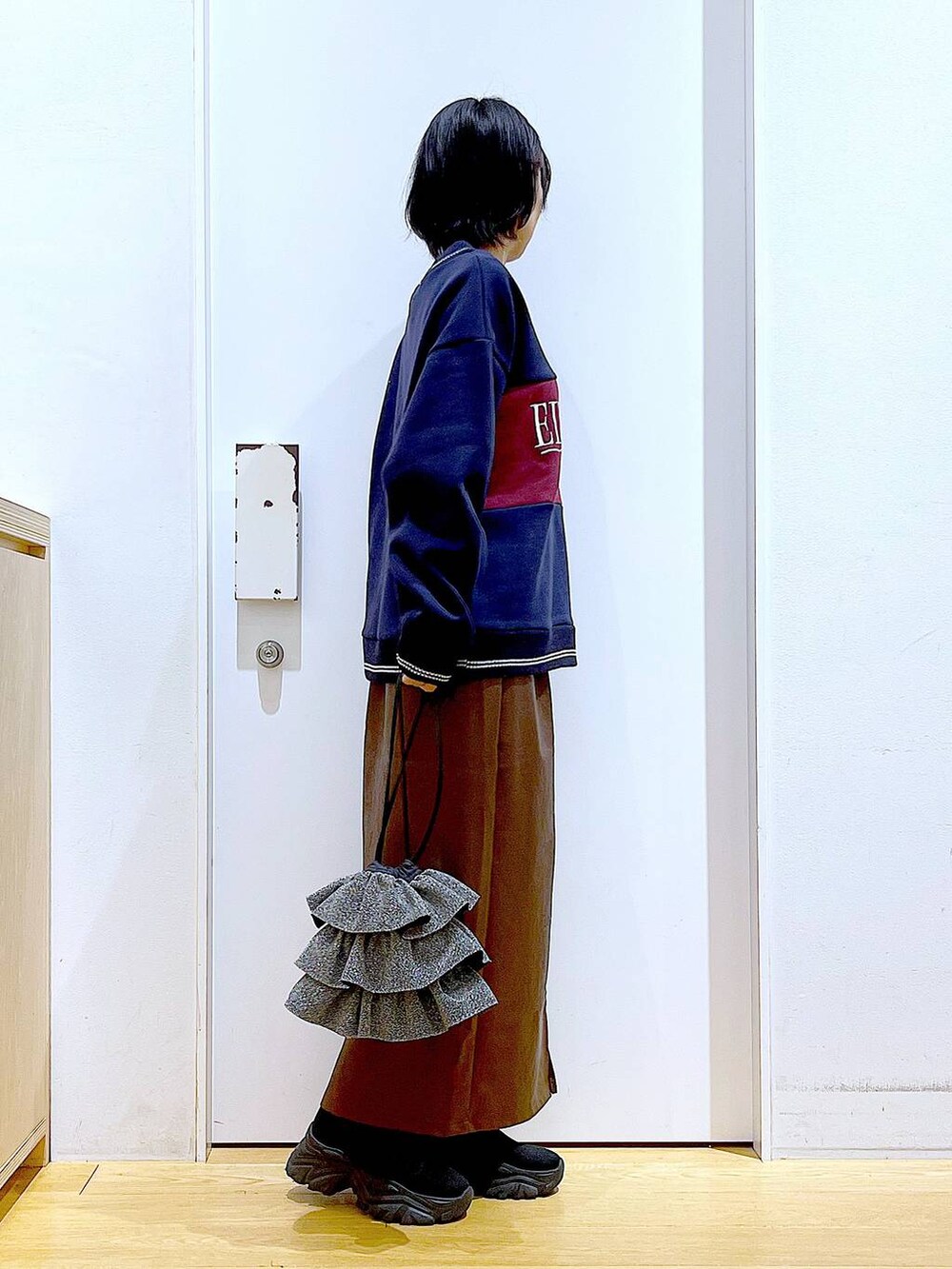 ブラウン系のスカート、ブラック系のブーツ、シルバー系のショルダーバッグを着用したレディースの冬コーディネートの4枚目の写真