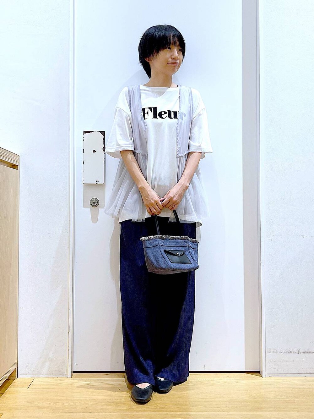 ブラック系のパンプス、ブルー系のショルダーバッグ、ホワイト系のTシャツ/カットソーを着用したレディースの夏コーディネートの2枚目の写真