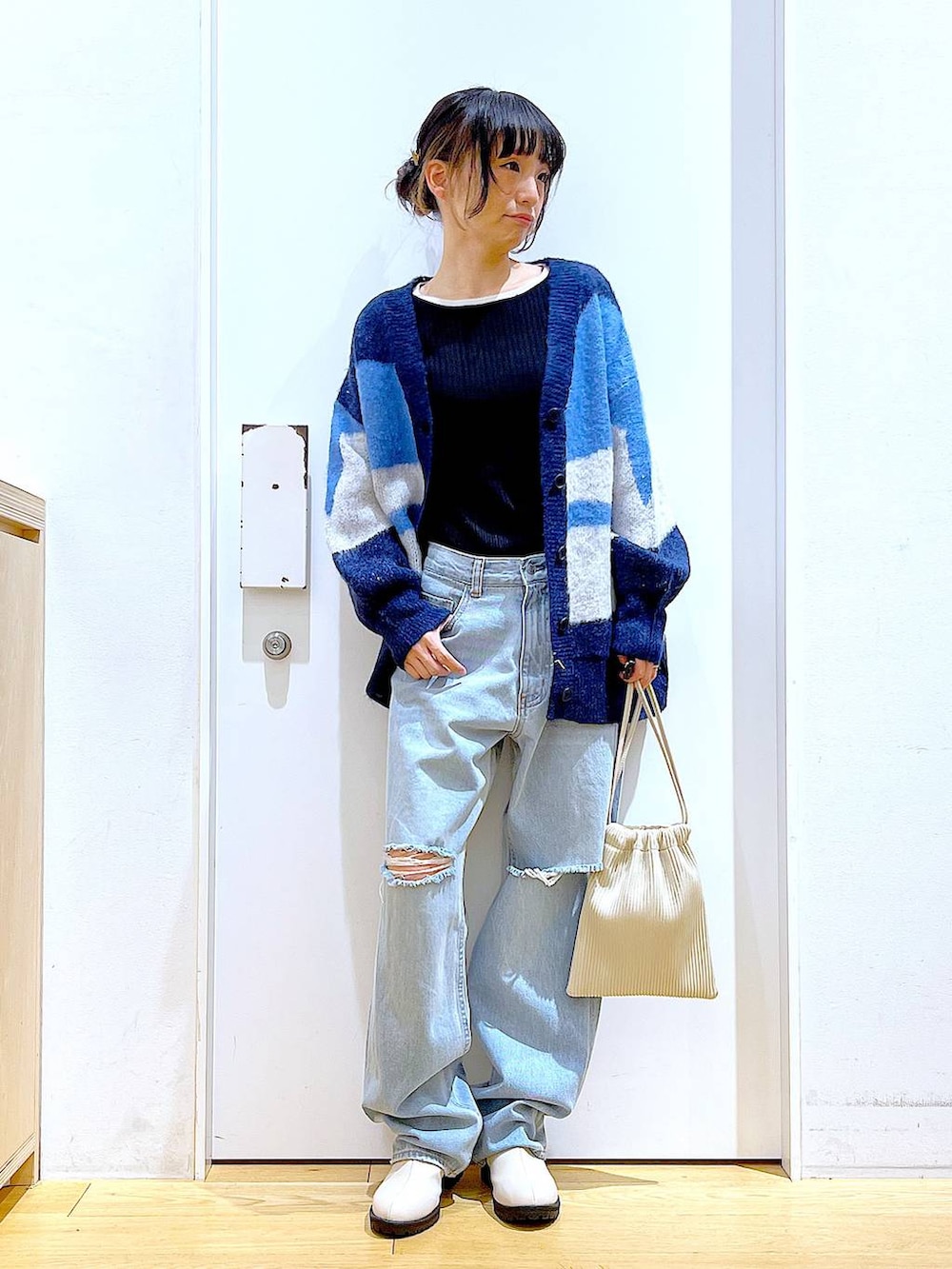 ベージュ系のショルダーバッグ、ベージュ系のブーツ、ブラック系のニット/セーターを着用したレディースの冬コーディネートの2枚目の写真