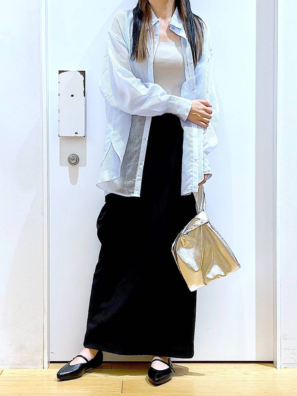 シルバー系のショルダーバッグ、ブラック系のパンプス、ブラック系のスカートを着用したレディースの春コーディネートの6枚目の写真
