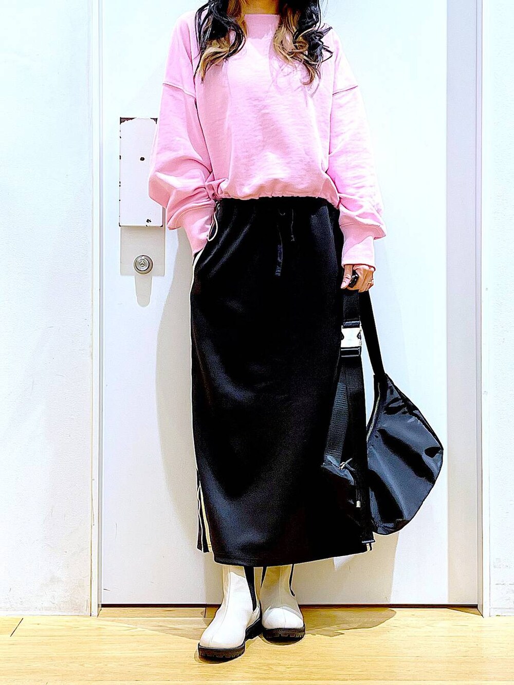 ピンク系のスウェット、ベージュ系のブーツ、ブラック系のショルダーバッグを着用したレディースの春コーディネートの6枚目の写真