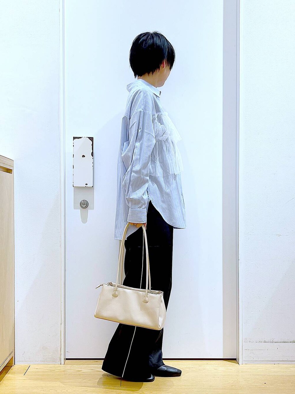 ブラック系のスラックス、ホワイト系のトートバッグ、ブラック系のパンプスを着用したレディースの春コーディネートの4枚目の写真