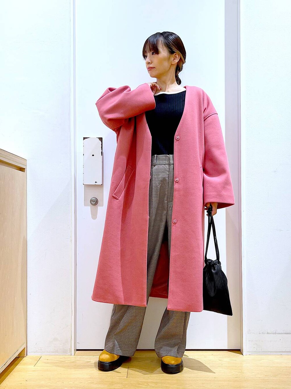 ブラック系のショルダーバッグ、ブラック系のニット/セーター、ベージュ系のスラックスを着用したレディースの冬コーディネートの2枚目の写真