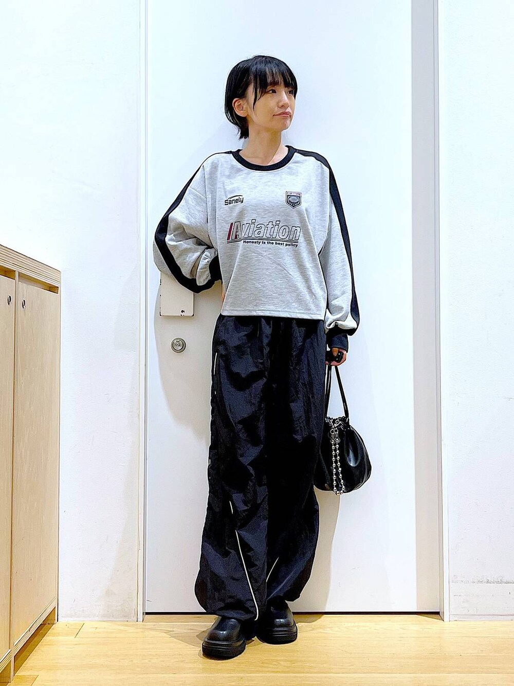 ブラック系のショルダーバッグ、ブラック系のブーツ、グレー系のTシャツ/カットソーを着用したレディースの秋コーディネートの2枚目の写真