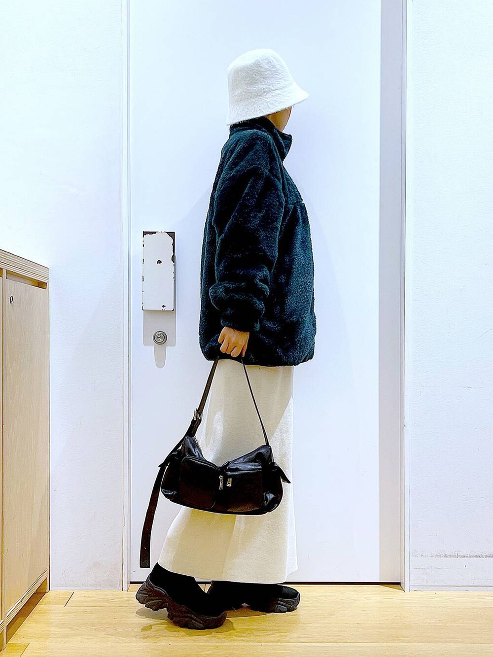 ブラック系のブーツ、ベージュ系のスカート、ブラック系のショルダーバッグを着用したレディースの冬コーディネートの4枚目の写真