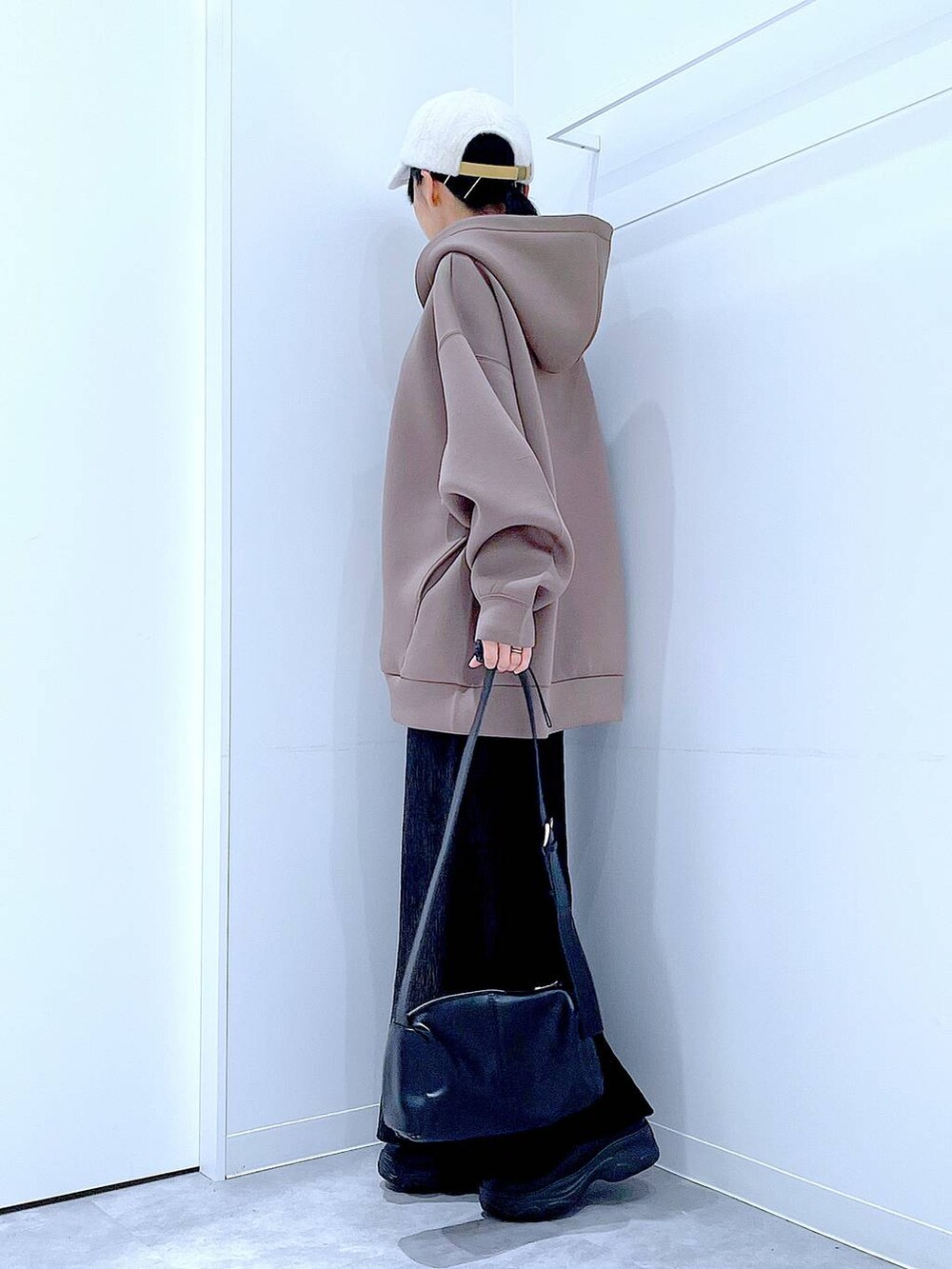 ブラック系のショルダーバッグ、ブラック系のブーツ、ブラウン系のパーカーを着用したレディースの秋コーディネートの3枚目の写真