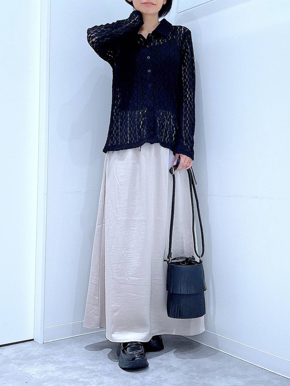 ブラック系のローファー、ブラック系のショルダーバッグ、ベージュ系のスカートを着用したレディースの秋コーディネートの6枚目の写真