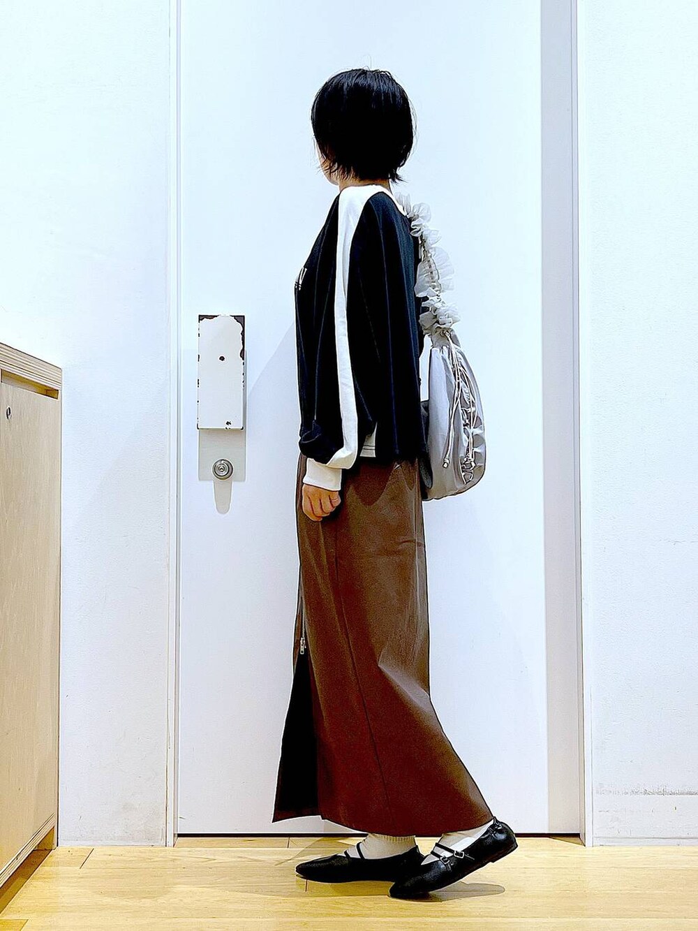 ブラウン系のスカート、ブラック系のパンプス、グレー系のショルダーバッグを着用したレディースの秋コーディネートの3枚目の写真