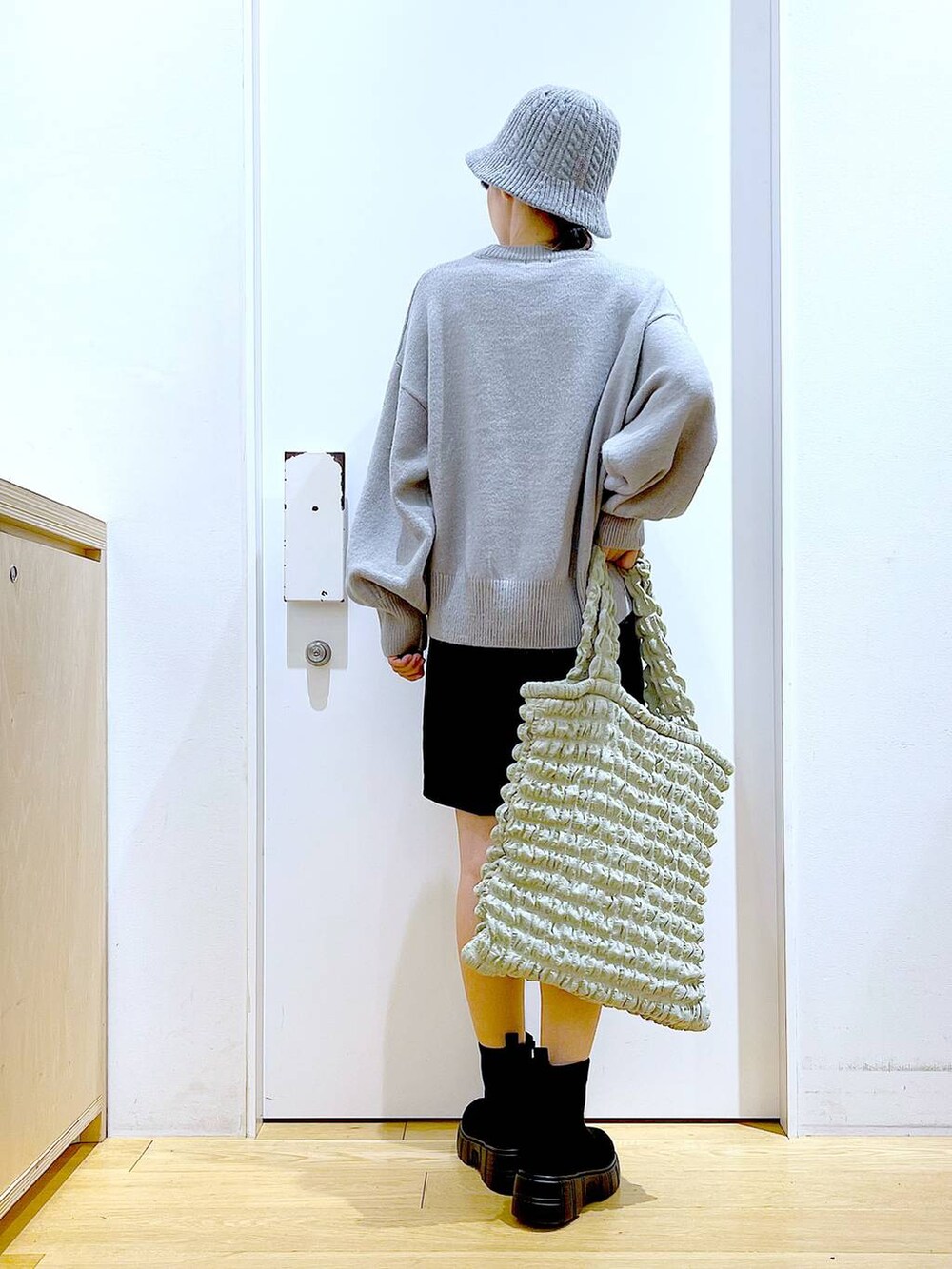 グリーン系のトートバッグ、ブラック系のブーツ、ブラック系のその他パンツを着用したレディースの冬コーディネートの5枚目の写真