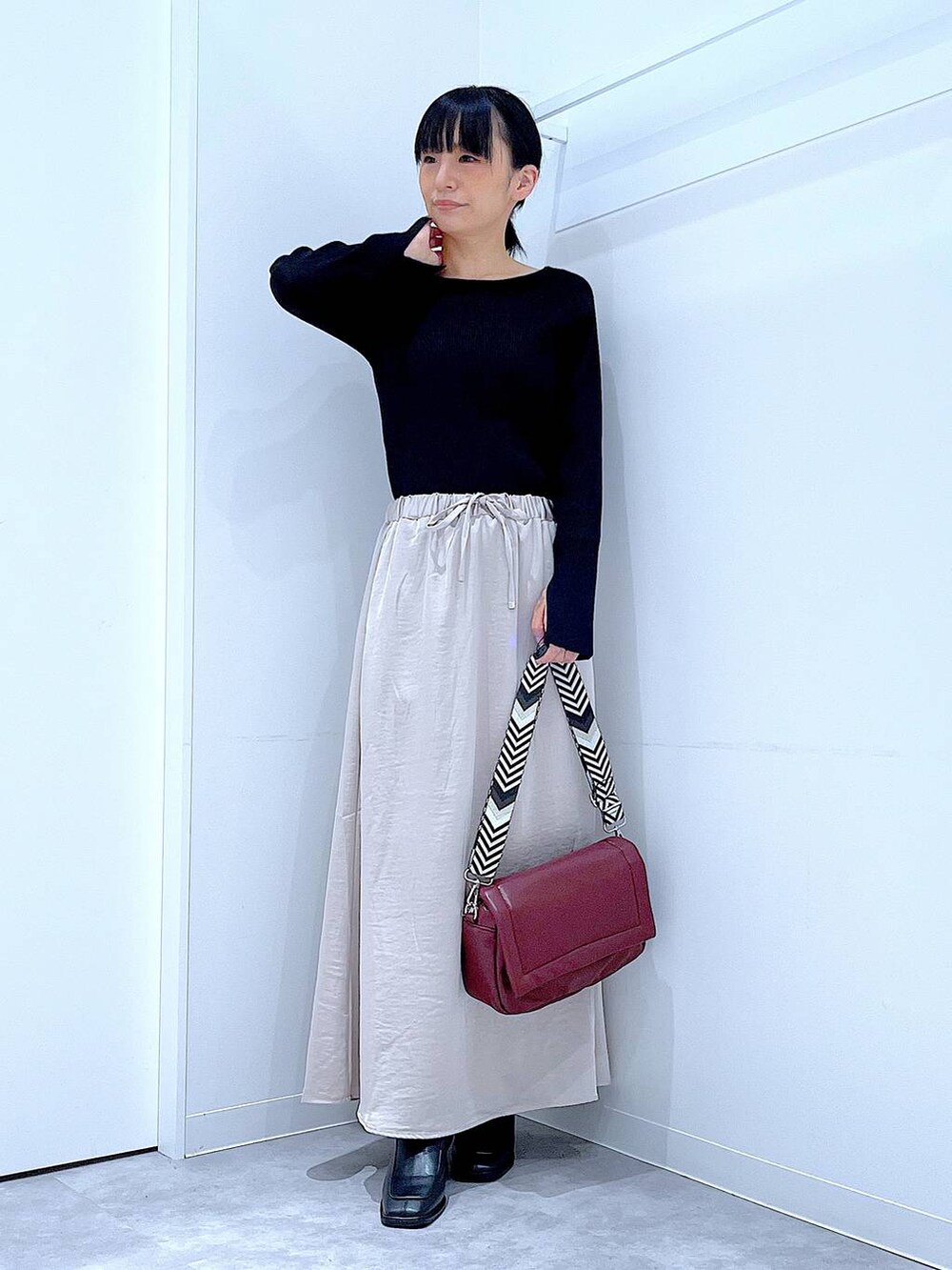ブラック系のニット/セーター、ベージュ系のスカート、レッド系のショルダーバッグを着用したレディースの秋コーディネートの2枚目の写真
