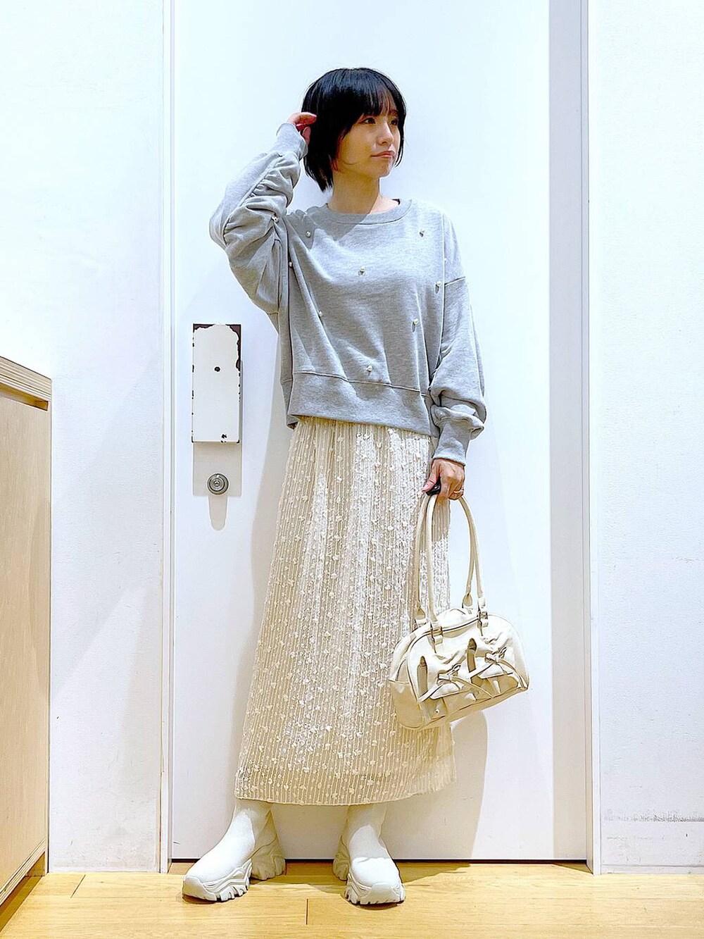 ホワイト系のハンドバッグ、グレー系のスウェット、ベージュ系のブーツを着用したレディースの秋コーディネートの2枚目の写真