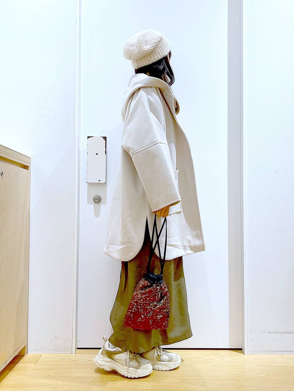 ホワイト系のその他アウター、ブラウン系のショルダーバッグ、ベージュ系のスニーカーを着用したレディースの冬コーディネートの4枚目の写真