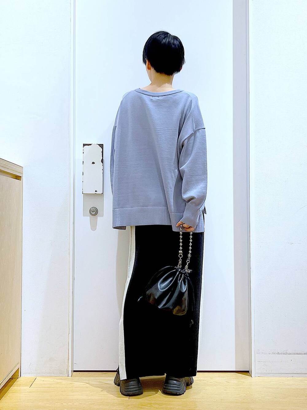 ブラック系のスカート、ブラック系のショルダーバッグ、ブラック系のブーツを着用したレディースの冬コーディネートの5枚目の写真