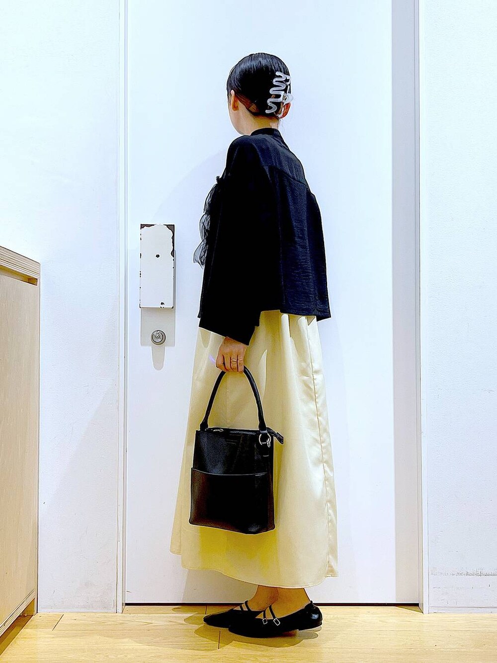 イエロー系のワンピース、ブラック系のショルダーバッグ、ブラック系のパンプスを着用したレディースの秋コーディネートの3枚目の写真