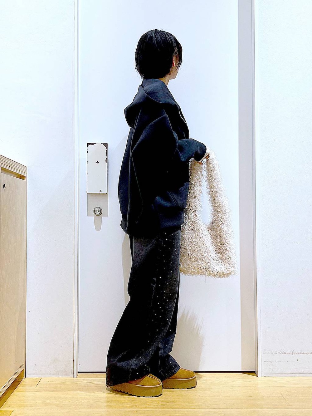 ベージュ系のスリッポン、ベージュ系のショルダーバッグ、ブラック系のデニムパンツを着用したレディースの冬コーディネートの4枚目の写真