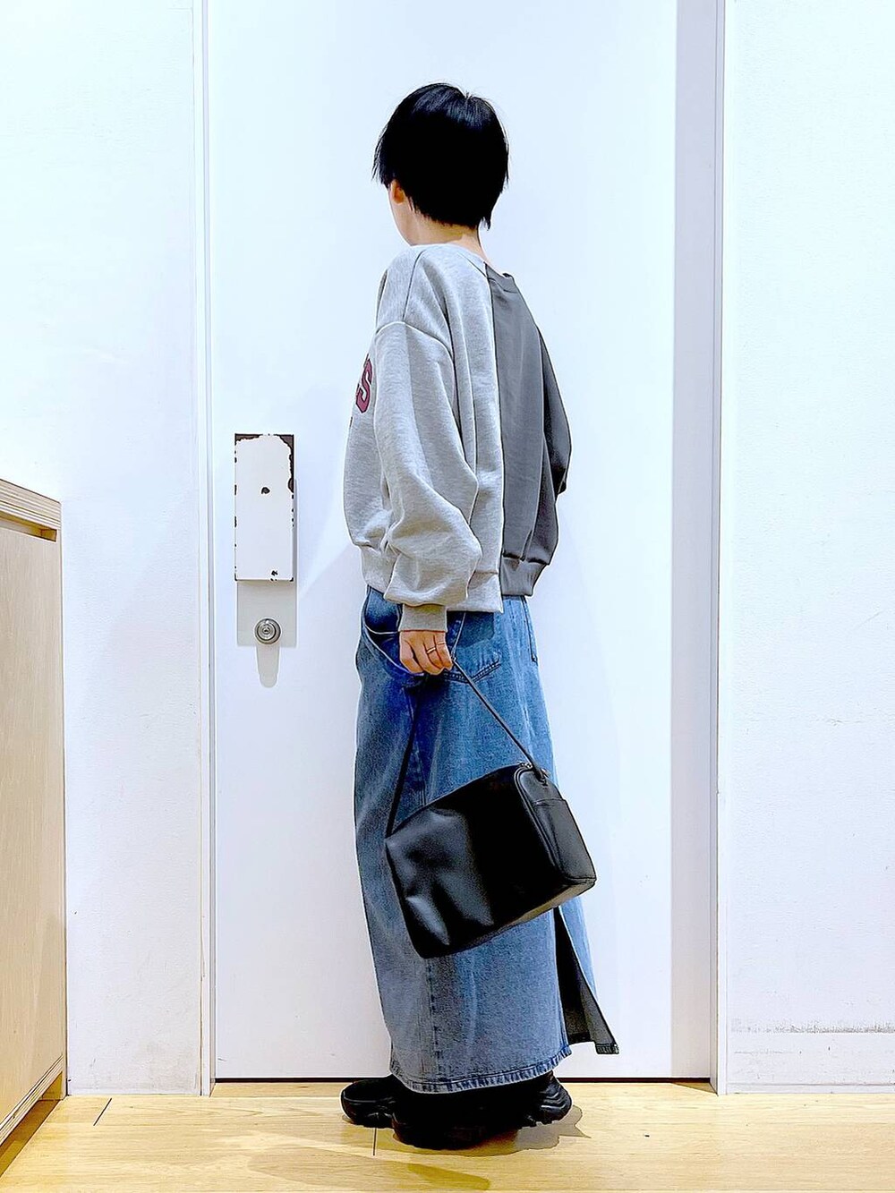 ブラック系のショルダーバッグ、ブラック系のブーツ、ブルー系のジャンパースカートを着用したレディースの春コーディネートの3枚目の写真