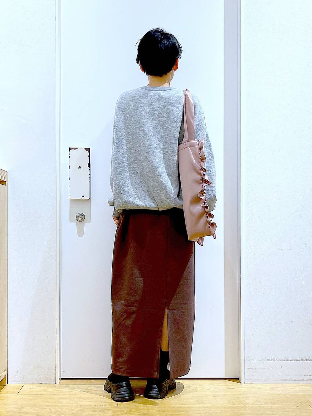 ブラック系のブーツ、ピンク系のトートバッグ、ブラウン系のスカートを着用したレディースの冬コーディネートの5枚目の写真