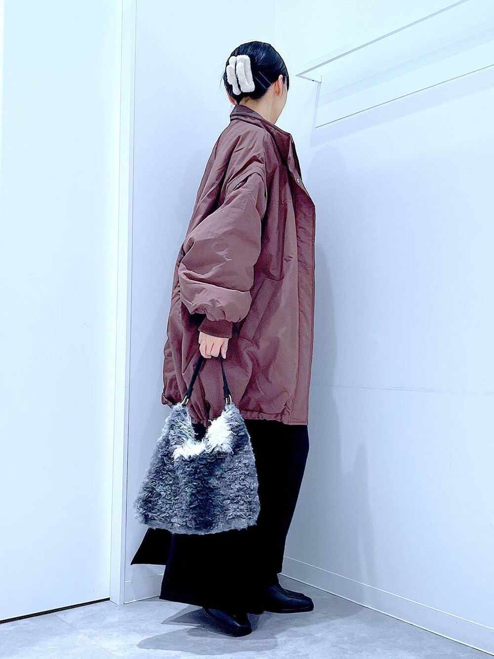 ブラウン系のブルゾン、ブラック系のブーツ、ブラック系のショルダーバッグを着用したレディースの冬コーディネートの4枚目の写真