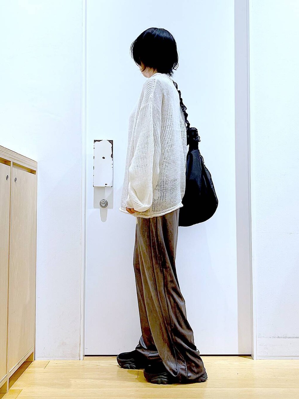 ブラック系のショルダーバッグ、ブラック系のブーツ、ホワイト系のニット/セーターを着用したレディースの冬コーディネートの3枚目の写真