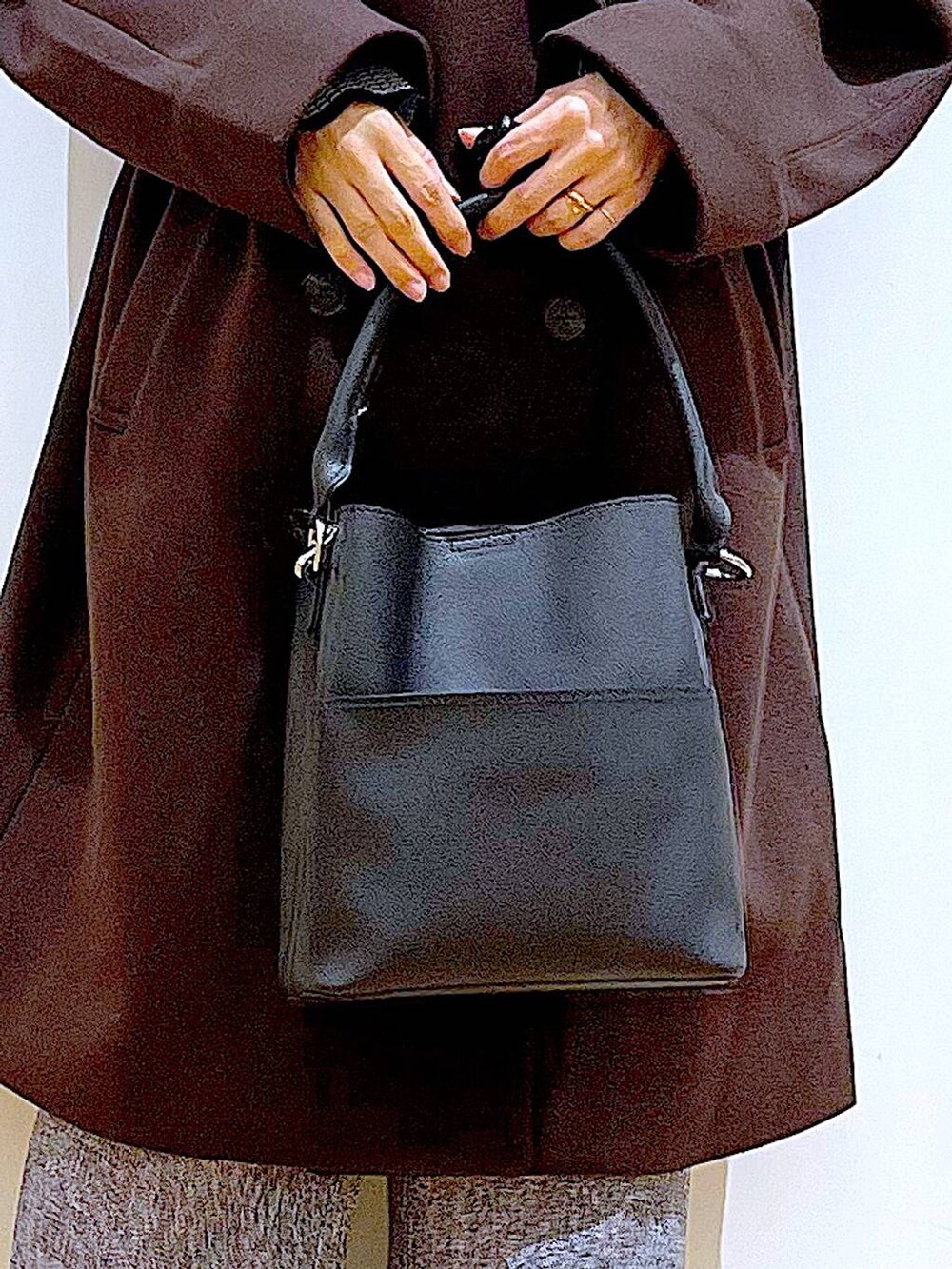 ブラウン系のステンカラーコート、ブラック系のショルダーバッグ、その他のニット/セーターを着用したレディースの冬コーディネートの9枚目の写真