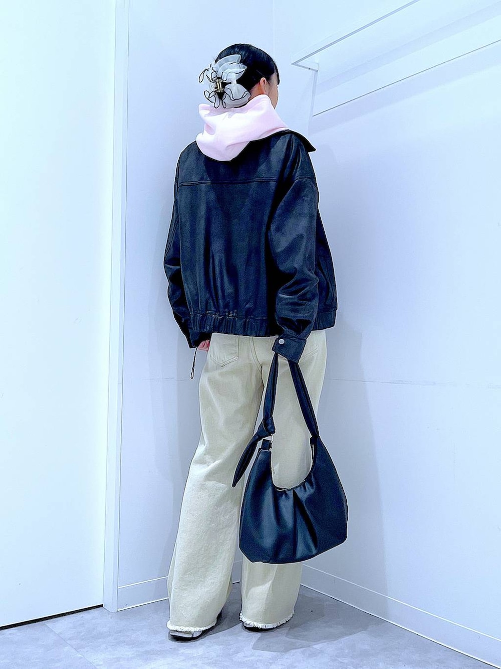 ブラック系のブルゾン、ベージュ系のデニムパンツ、ピンク系のパーカーを着用したレディースの冬コーディネートの5枚目の写真