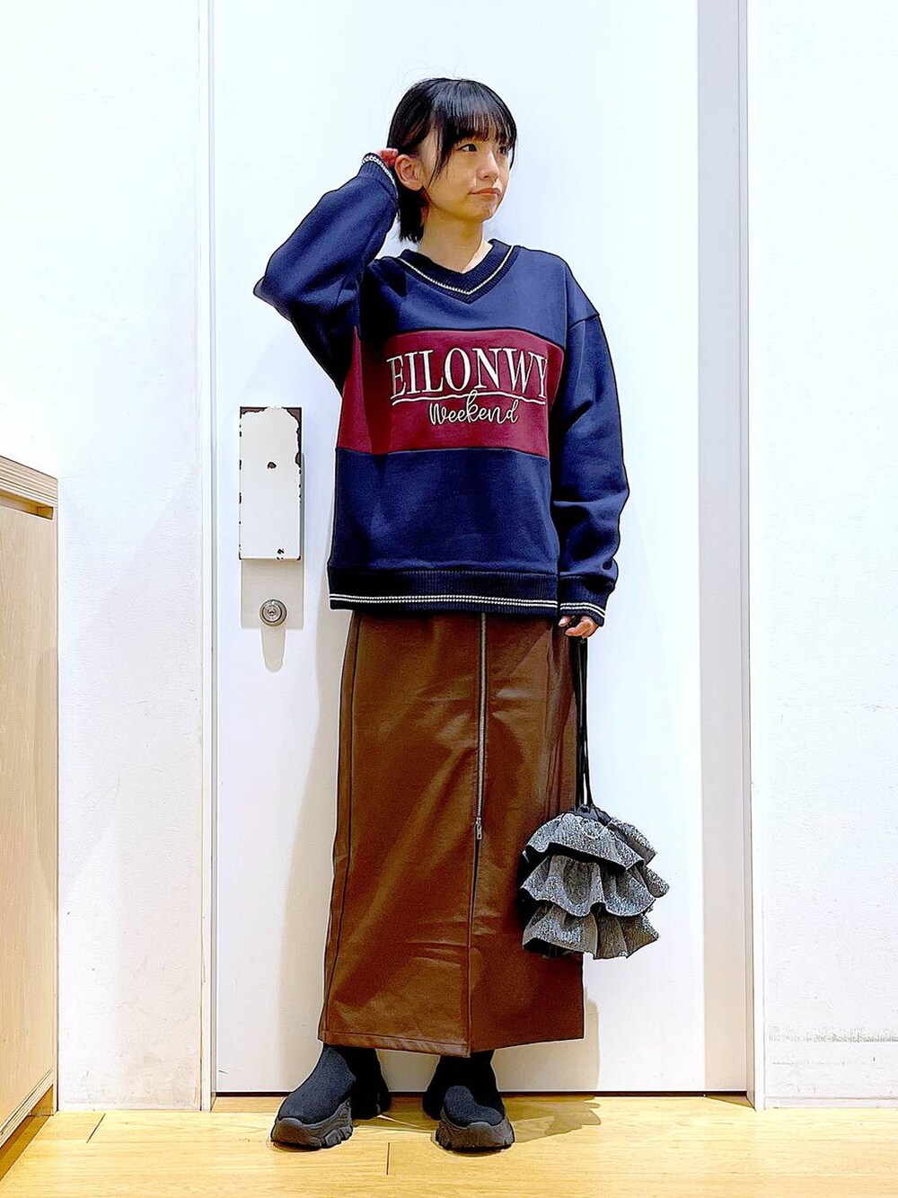 ブラウン系のスカート、ブラック系のブーツ、シルバー系のショルダーバッグを着用したレディースの冬コーディネートの2枚目の写真