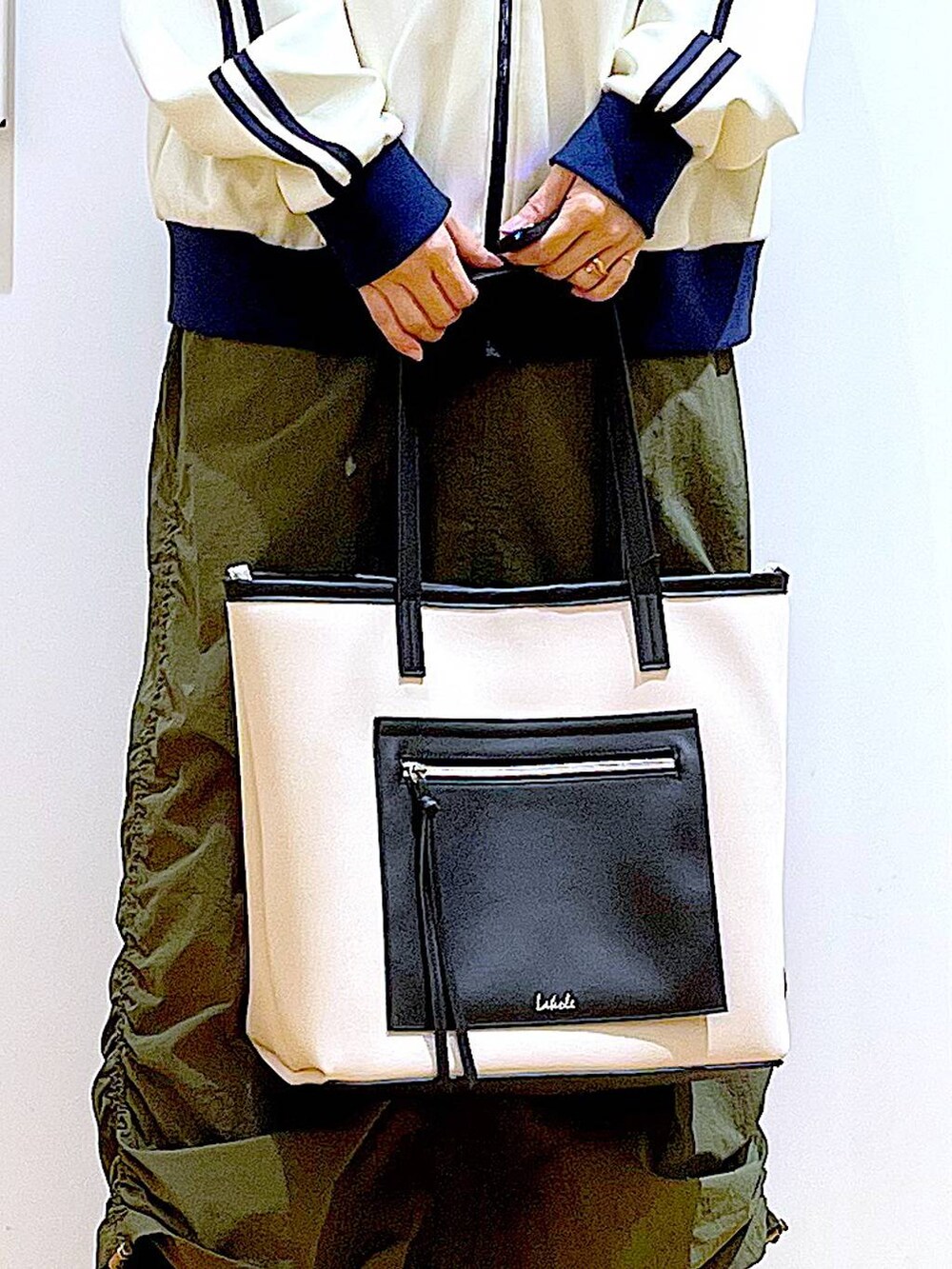 ホワイト系のトートバッグ、ブラック系のブーツ、グリーン系のスカートを着用したレディースの冬コーディネートの9枚目の写真