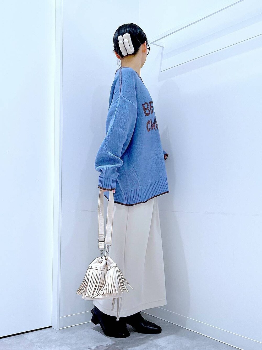 ベージュ系のスカート、ブラック系のブーツ、ホワイト系のショルダーバッグを着用したレディースの冬コーディネートの4枚目の写真